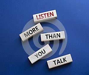 Listening skills symbol. Concept words Listen more than you Talk on wooden blocks. Beautiful deep blue background. Business and
