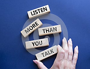 Listening skills symbol. Concept words Listen more than you Talk on wooden blocks. Businessman hand. Beautiful deep blue