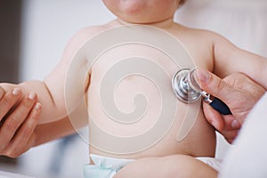 Listening to babys heart beat. a doctor examining an infant girl with a stethoscope.