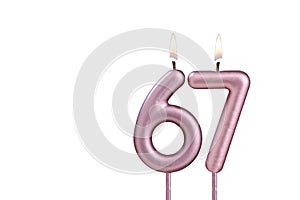 Lit birthday candle - Candle number 67 on white background