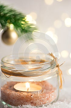 Lit candle in crystal jar candleholder hanging Christmas tree branch with golden ball. Snow winter forest. Lights. New Year