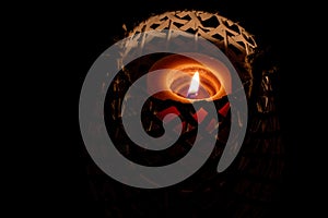 A lit Candle sitting in a basket in the dark, used during a power outage