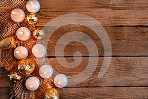 Lit candles, Christmas tree Golden baubles and burlap on a wooden background. New year`s flat layout with space for text