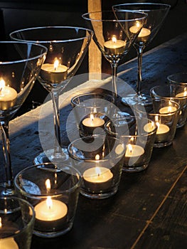 Lit candles in glasses on rustic wooden