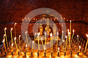 Lit church candles in a gilded candlestick in a temple in the dark. yellow wax lighted candles stand in the church, glow