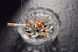 Lit cigarette with smoke lying on an ashtray