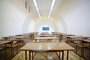 Lit classroom with rows of wooden tables for photo