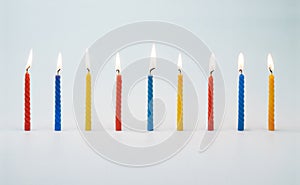 Lit colorful birthday cake candles. Background image with a birthday concept.