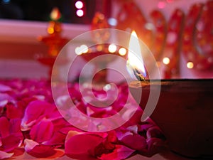 A lit diya on bed of roses