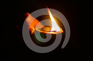 Lit diya or clay lamp on the palm of a person