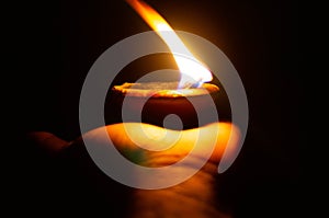 Lit diya or clay lamp on the palm of a person
