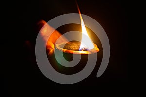 Lit diya or clay lamp on the palm of a person