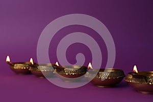 Lit diya lamps on purple background. Diwali celebration