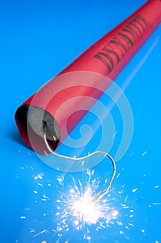 Lit dynamite stick on a blue background