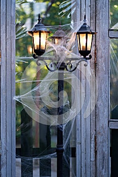 The lit electric lantern is wrapped in cobwebs
