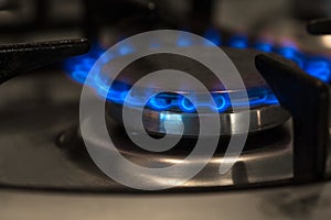 Lit gas stove on a dark background. Blue flame of gas on a cooker.