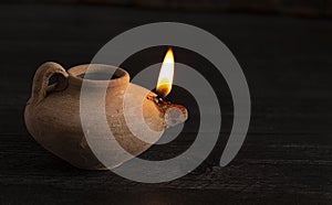 A Lit Handmade Oil Lamp from the Middle East on a Dark Table