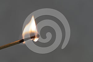 A lit match against a gray background. Fire burns.