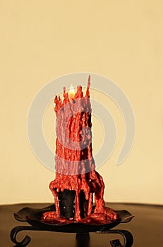 Lit peach colored candle with melting wax dripping down