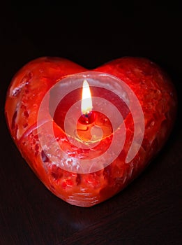 Lit red heart candle, dark background