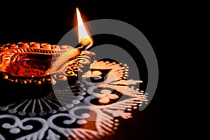 A lit terracotta lamp or clay diya placed on black background. festival of lights or deepawali concept