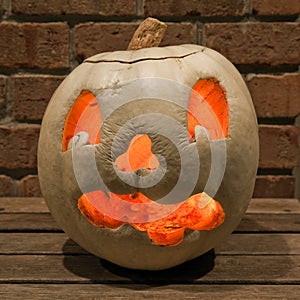 Lit white jack o'lantern on a bench