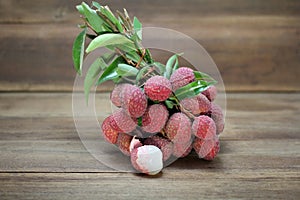 Litchi chinensis fruit with leaves peeled to show the flesh white on wooden background.