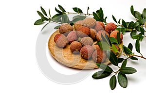 Litchi  lie on a wooden plate, around a sprig with leaves on a white background or on a black background