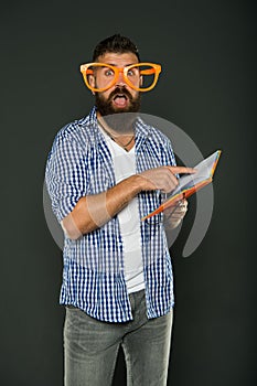 Literary club. Reading book as hobby. Study is fun. Hipster bearded man funny eyeglasses hold notepad or book. Read this