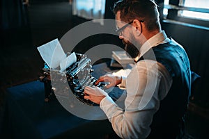Literature author in glasses typing on typewriter