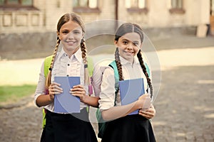 after literature lesson. prepare to exam. study together outdoor. girls with books and backpacks. children hold notebook