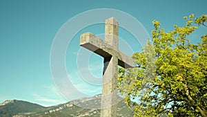 Lithic cross monument against mountains and trees in park