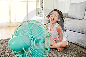 Litle girl laughing and sitting in front of fan.