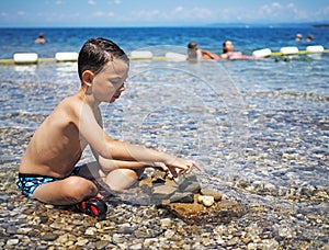 Littel boy playing in water with stones