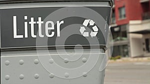 litter caption writing and recycle symbol on garbage with blurred traffic-