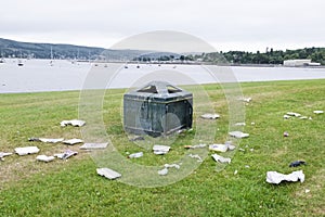 Litter garbage rubbish in park outside of bin lying on ground green grass ruin view seaside resort uk