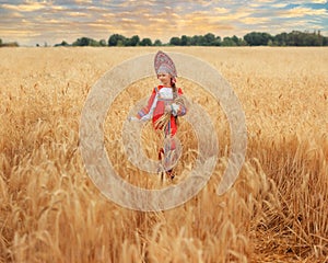 Littl girl kid in Russian national sarafan and a kokoshnik standing in a golden wheat field in summer day