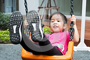 Little 4 years girl wear pink t-shirt playing swing at outdoor playground. kids love to swing. she laughing with happiness feeling