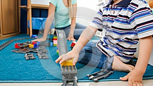 Little 4 years old boy palying with mother in toy train and railroad