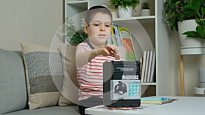 Little 6 year old boy saving his money by putting it in a toy safe. Financially literate children