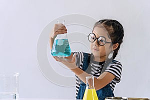 Little 6s girl with microscope holding laboratory bottle with water experiment study scientists at school. Education science