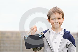 Little 7 years boy holding a empty blackboard