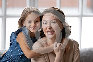 Little 7s girl embracing smiling attractive mature granny.