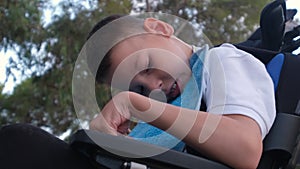 Little 9s boy with cerebral palsy sit in wheelchair outdoor