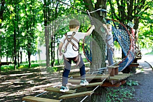 Little active boy who climbs on a rope the way to the amusement Park