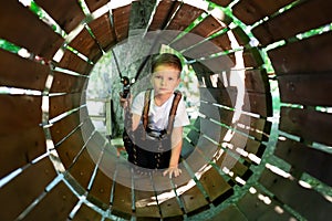 Little active boy who climbs on a rope the way to the amusement Park in the summer.