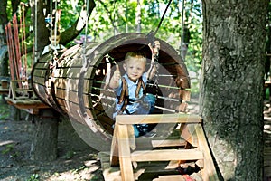 Little active boy who climbs on a rope the way to the amusement Park in the summer.