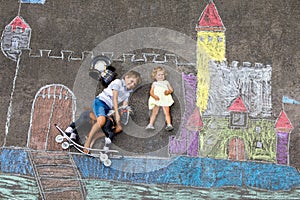 Little active kid boy and cute toddler baby girl drawing knight castle and fortress with colorful chalks on asphalt