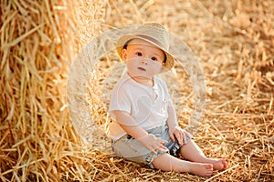 Little adorable baby boy with big brown eyes in a hat sits in a