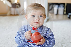 Little adorable baby girl eating big red apple. Vitamin and healthy food for small children. Portrait of beautiful child